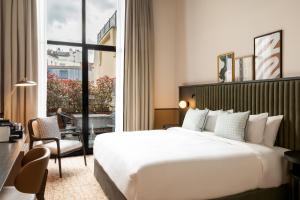 ブローニュ・ビヤンクールにあるLe Parchamp, a Tribute Portfolio Hotel, Paris Boulogneの大きなベッドと大きな窓が備わるホテルルームです。