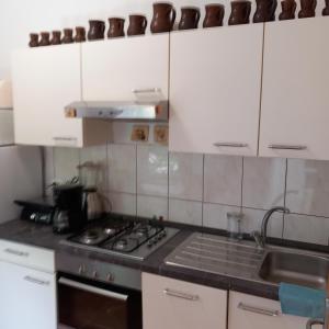 a kitchen with white cabinets and a stove top oven at Apartman Selce in Selce