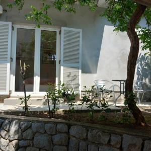 a porch with a table and a tree in front of a house at Apartman Selce in Selce
