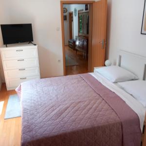 a bedroom with a bed and a dresser and a television at Apartman Selce in Selce