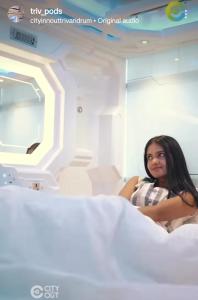 una mujer sentada en una cama de hospital en TRIVPODS Capsule Hotel, en Trivandrum