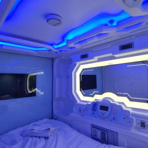 a room with a bed and a tv and lights at TRIVPODS Capsule Hotel in Trivandrum