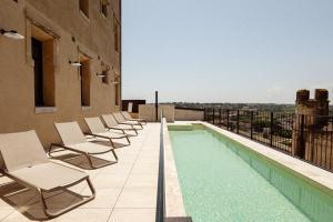einen Balkon mit Stühlen und einen Pool auf einem Gebäude in der Unterkunft Hôtel La Prison in Béziers
