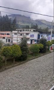ein weißes Gebäude mit Bäumen vor einer Straße in der Unterkunft Casa campestre en las faldas del Taita Imbabura 3 in Otavalo