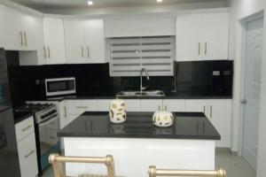 uma cozinha com armários brancos e um balcão preto em Penthouse con Piscina en Cotui em Cotuí