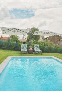 basen z 2 krzesłami i 2 parasolami w obiekcie Casa Rural Horta De Arriba w mieście Porta