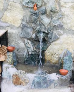 a waterfall in a stone wall with two orange pots at Honi in Ijevan
