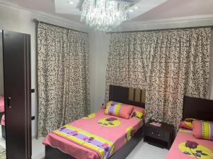 a bedroom with a pink bed and a chandelier at شقة فندقية 3 غرف كمبوند الخمائل in Kafr Abū ʼumaydah