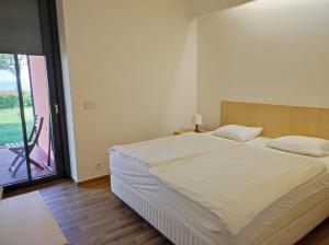 a bedroom with a bed and a large window at Soleil Apartmanok Balatonlelle in Balatonlelle