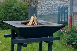 a black grill with a bunch of wood in it at Maison la Taissotine in Leucamp