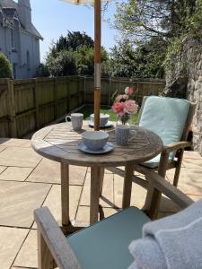 a wooden table with two chairs and flowers on a patio at The Stables - Detached Cottage with Private Garden & Hot Tub in St Austell