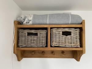 a wooden shelf with two baskets and a mattress at The Stables - Detached Cottage with Private Garden & Hot Tub in St Austell
