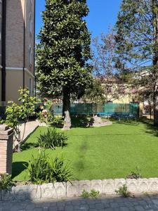 a green yard with a tree and a building at Cucchiari Suite 7A in Modena