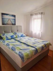 Una cama en un dormitorio con colcha. en Andrija Apartment, en Krnica