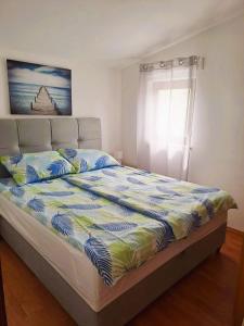 a bed in a bedroom with a bedspread on it at Andrija Apartment in Krnica