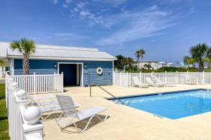 a swimming pool with chairs and a blue house at The Emerald Cottage in Mexico Beach