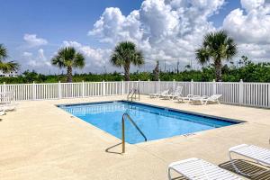 a swimming pool with chairs and a fence and palm trees at The Emerald Cottage in Mexico Beach