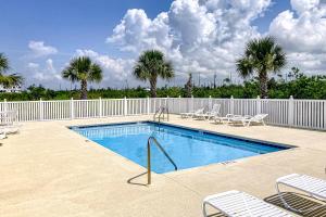 una piscina con sedie, recinzione e palme di The Emerald Cottage a Mexico Beach