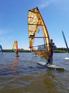 a group of people on surfboards with a sail on the water at Wind4You in Dąbki