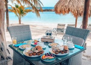 a table with plates of food on the beach at Curacao Avila Beach Hotel in Willemstad