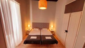 a bedroom with a bed and two lamps and a window at Hostel A Casa da Árvore in Faro