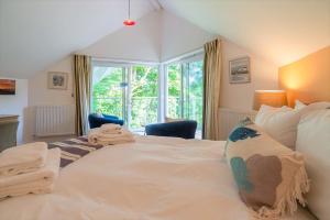 a bedroom with a large white bed and a window at Trewhiddle Retreat V11 by Together Travel - Luxury 4-Bedroom Villa in St Austell