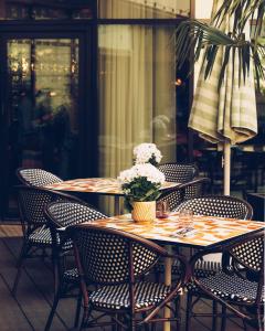 une table avec des chaises et un vase de fleurs. dans l'établissement Le Parchamp, a Tribute Portfolio Hotel, Paris Boulogne, à Boulogne-Billancourt