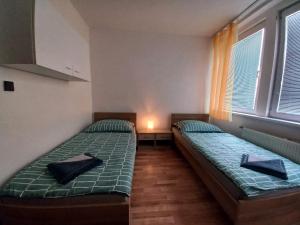 two twin beds in a room with two windows at Penzión Tina in Prešov