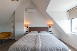 ein Schlafzimmer mit einem Bett mit weißer Bettwäsche und einem Stuhl in der Unterkunft De Zuivelhandel in Petten