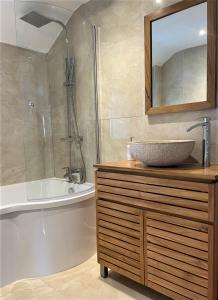 uma casa de banho com um lavatório, uma banheira e um espelho. em The Little Seahorse - Newly Renovated Cottage 5mins Walk The Beach with Hot Tub em Tywardreath