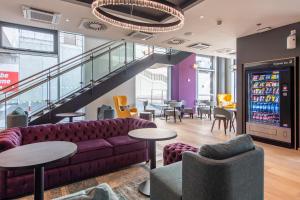 eine Lobby mit einem Sofa, Tischen und Stühlen in der Unterkunft Premier Inn Stuttgart City Centre in Stuttgart