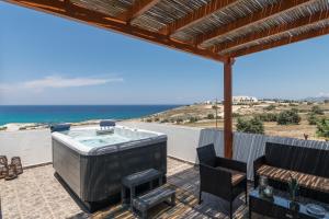 a hot tub on a patio with a view of the ocean at Iliovasilema Studios in Mytakas