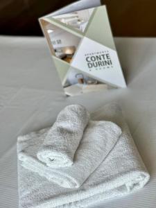 una pila de toallas sentadas encima de una cama en Conte Durini Apartments & Rooms, en Arcore
