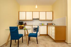 cocina con mesa y 2 sillas azules en Nisos Sunset Apartments Agios Gordios en Corfú