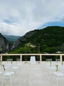 a group of white chairs and a table and a mountain at Khidikari Hotel in Ambrolauri