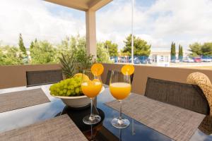 a table with two glasses of orange juice and a bowl of fruit at Holiday Home Bibano in Bibinje
