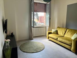 sala de estar con sofá amarillo y ventana en Rosa di Parma en Parma