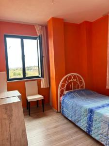 - une chambre aux murs orange avec un lit et une chaise dans l'établissement Enez’de Müstakil Villa, à Enez