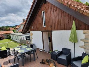 a patio with a table and chairs and a dog laying on a deck at Au Château in Lajoux