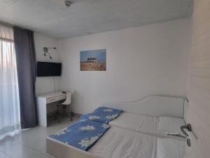 a white bedroom with a bed and a desk at Appart-Hotel Holiday in Lignano Sabbiadoro
