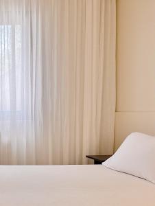 sypialnia z białym łóżkiem i oknem w obiekcie Quomorari w mieście Barletta