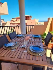 een houten tafel met borden en wijnglazen op een balkon bij Ático Estrella sunset in Corralejo