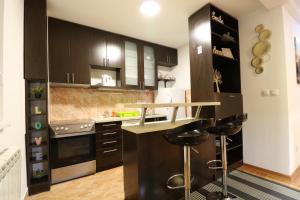 a kitchen with black cabinets and a counter with stools at Flat 23 in Belgrade