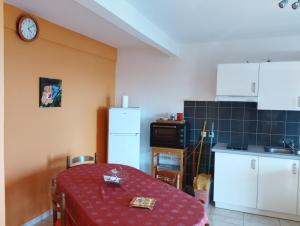 a kitchen with a table and a refrigerator and a clock at Le Papillon Bleu in Bouillante