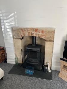 a fireplace with a stove in a living room at Triple Deck Cottage - 2mins from Mevagissey Harbour in Mevagissey