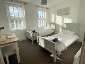 a bedroom with two beds and a desk and windows at Triple Deck Cottage - 2mins from Mevagissey Harbour in Mevagissey