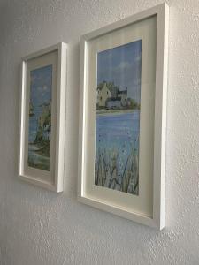 two framed paintings on a wall at Triple Deck Cottage - 2mins from Mevagissey Harbour in Mevagissey