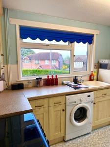 a kitchen with a washing machine and a window at Rochester town centre beautiful 3-Bedroom House with garden in Strood