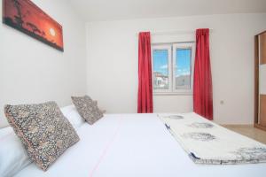 - une chambre avec un lit blanc et des rideaux rouges dans l'établissement Dusica apartments, à Tribunj