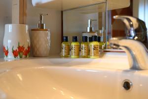 a bathroom sink with bottles of soap and a mirror at Nisos Sunset Apartments Agios Gordios in Corfu Town